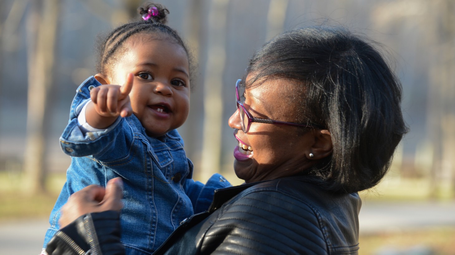 Smiling mom holding toddler, who is pointing