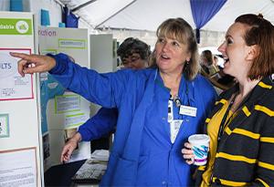 2 women pointing to ubt fair board