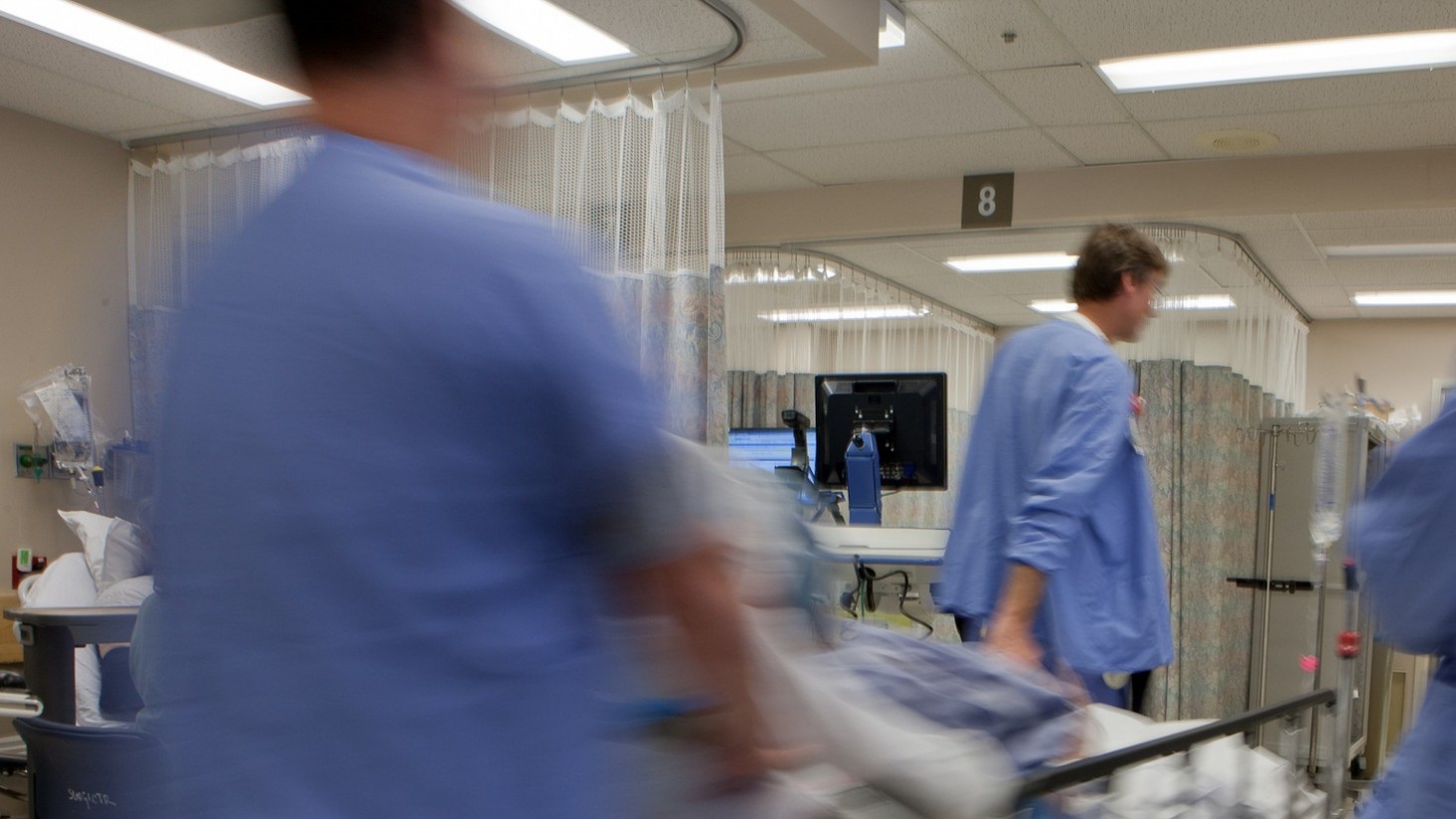 health care workers wheeling a patient on a gurney into surgery 