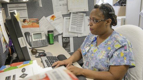 Nurse typing and looking at a computer screen 